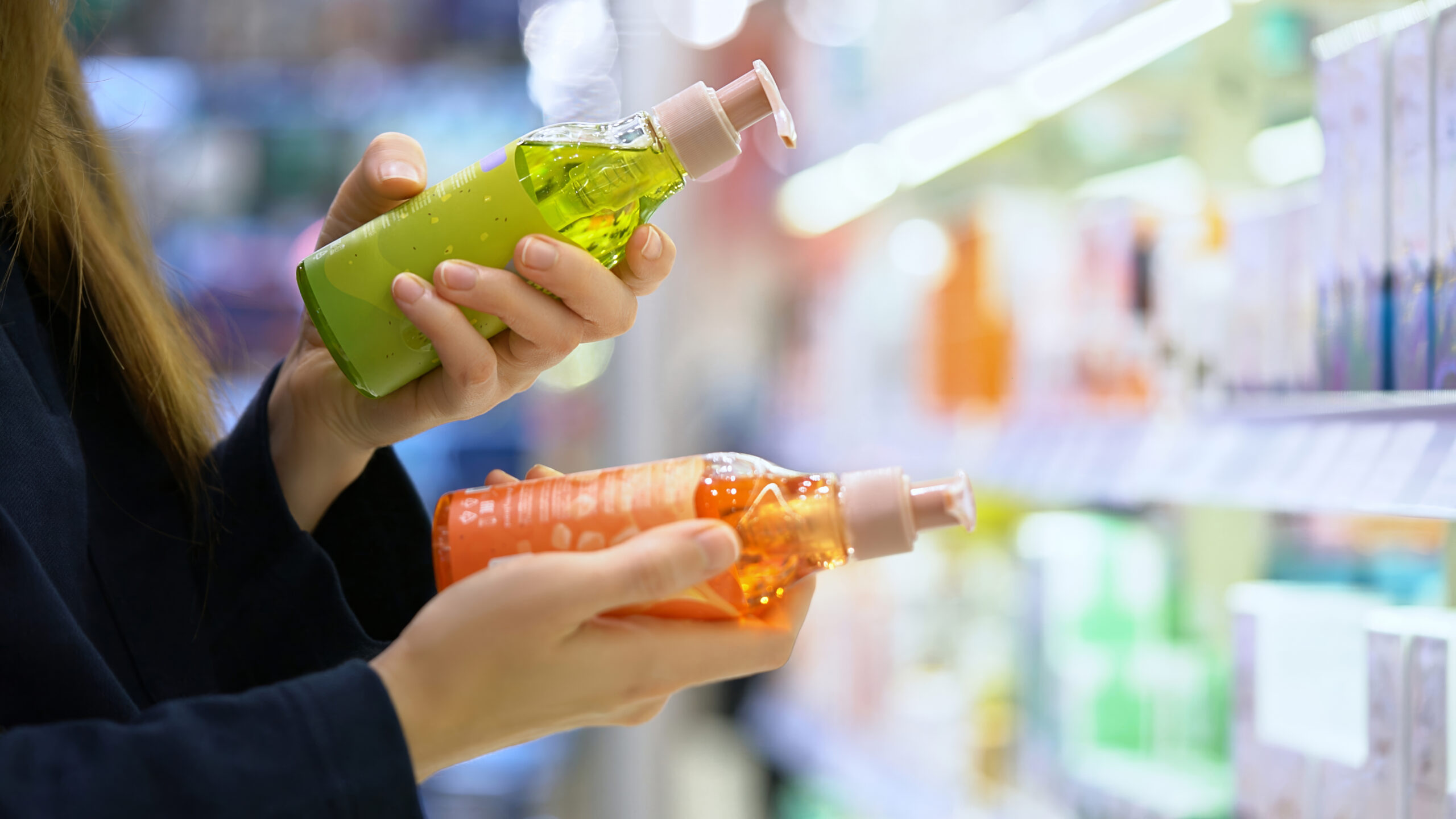female customer compares two different shampoo bottles