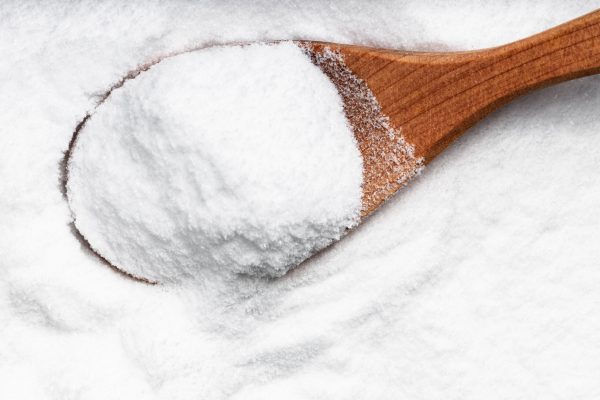 top view of wood spoon with dextrose sugar close up on pile of sugar